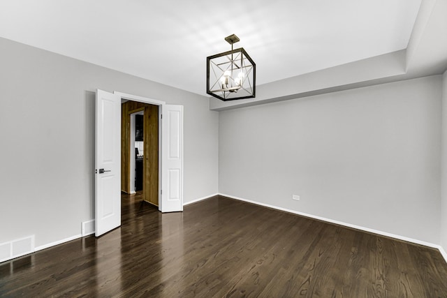 unfurnished room featuring a notable chandelier and dark wood-type flooring