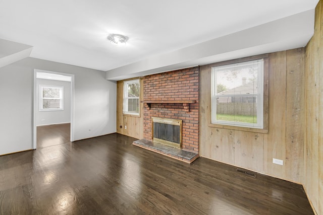 unfurnished living room with wood walls, dark hardwood / wood-style floors, and a brick fireplace