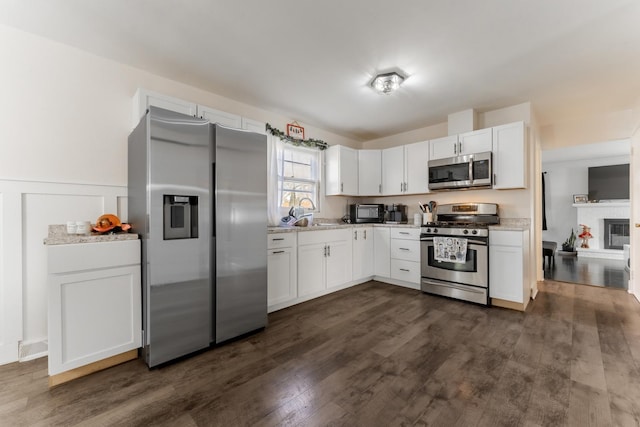 kitchen featuring light stone countertops, dark hardwood / wood-style flooring, white cabinetry, and appliances with stainless steel finishes