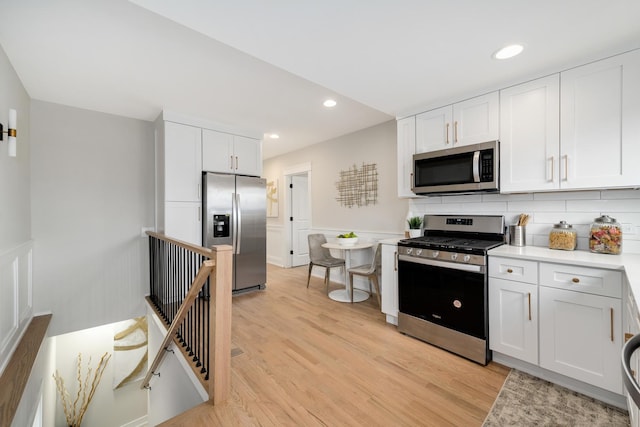 kitchen featuring light hardwood / wood-style floors, white cabinetry, stainless steel appliances, and tasteful backsplash