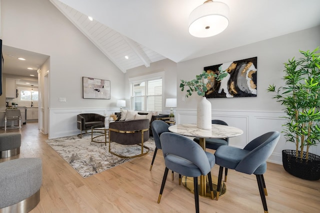 dining room featuring vaulted ceiling with beams and light wood-type flooring