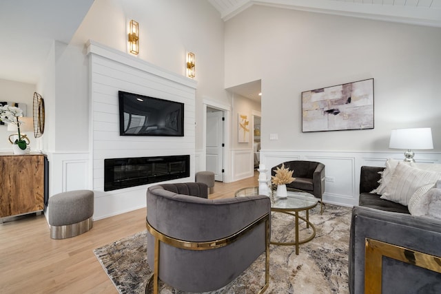 living room with a large fireplace, light hardwood / wood-style flooring, and vaulted ceiling