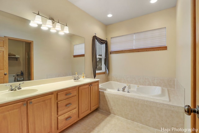 bathroom with tile patterned floors, vanity, and a relaxing tiled tub