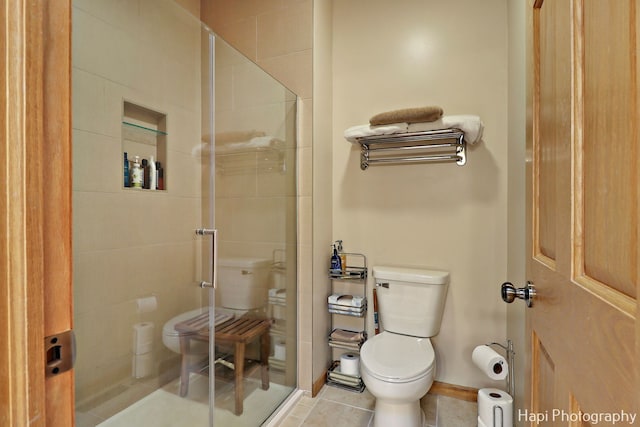 bathroom featuring tile patterned flooring, an enclosed shower, and toilet