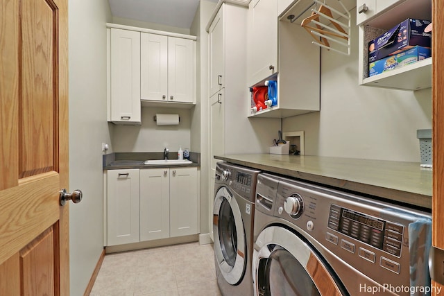 laundry room with cabinets, light tile patterned floors, sink, and washing machine and clothes dryer