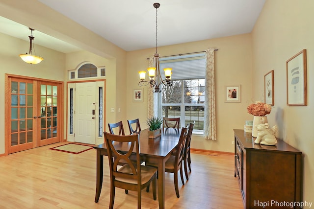 dining room with french doors, light wood-type flooring, and a notable chandelier