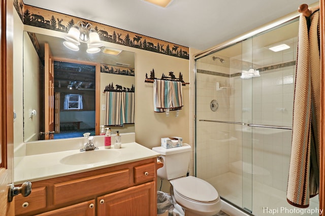 bathroom featuring vanity, toilet, and a shower with shower door