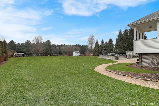 view of yard featuring a covered pool and a storage shed