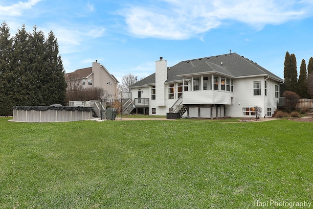 rear view of house with a lawn, a pool side deck, and a sunroom