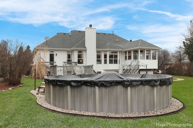 back of property with a lawn, a pool side deck, and a sunroom