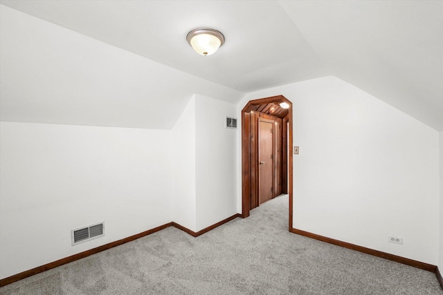 additional living space featuring lofted ceiling and light carpet