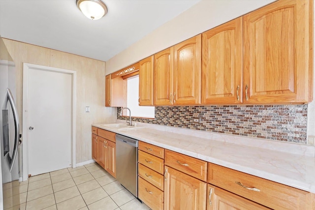 kitchen featuring appliances with stainless steel finishes, backsplash, light stone counters, sink, and light tile patterned flooring