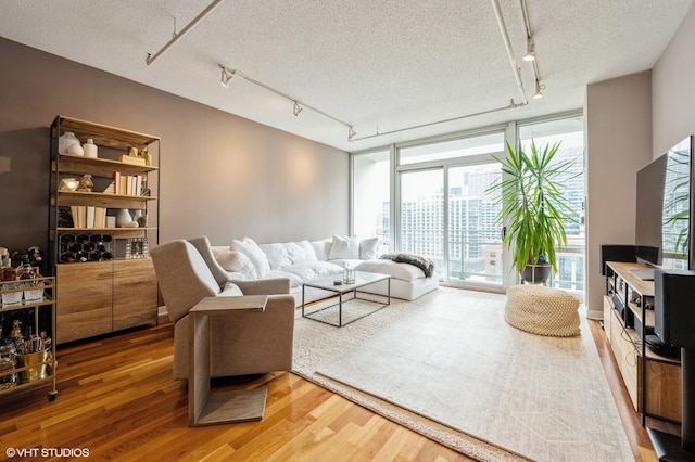 living room featuring rail lighting, expansive windows, a textured ceiling, and hardwood / wood-style floors