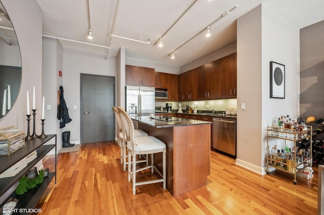 kitchen with a kitchen breakfast bar, a kitchen island, stainless steel appliances, and light hardwood / wood-style flooring