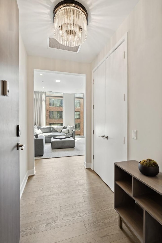 hall featuring an inviting chandelier and light wood-type flooring