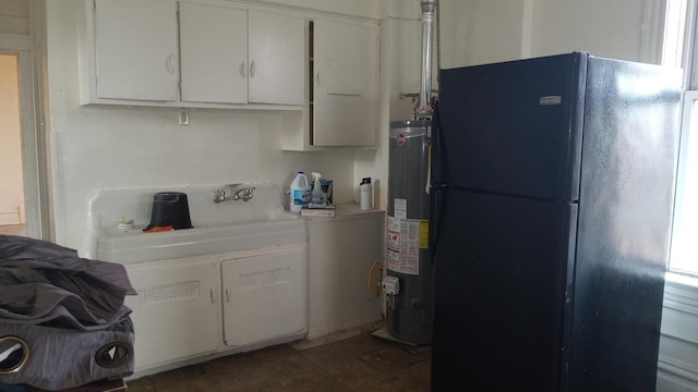 kitchen featuring gas water heater, black refrigerator, white cabinets, and dark tile patterned flooring