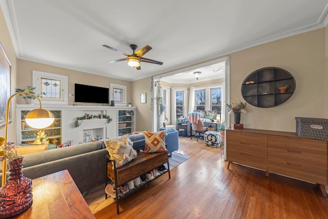 living room featuring a fireplace, hardwood / wood-style flooring, ceiling fan, and ornamental molding