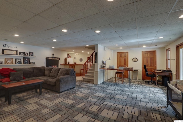 living room with a paneled ceiling and dark colored carpet