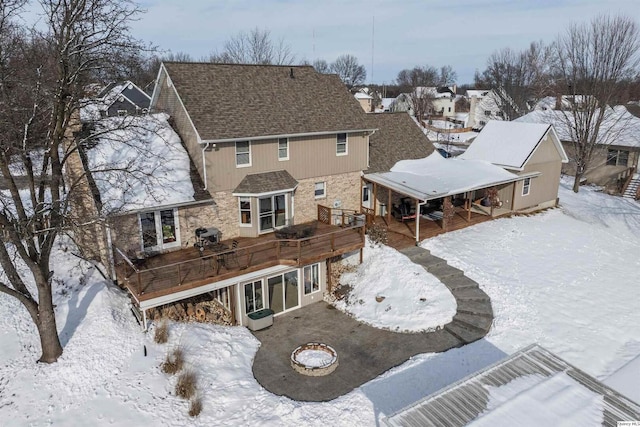 snow covered property featuring a deck and an outdoor fire pit