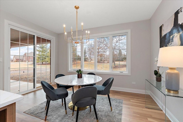 dining room with plenty of natural light, light hardwood / wood-style floors, and a chandelier