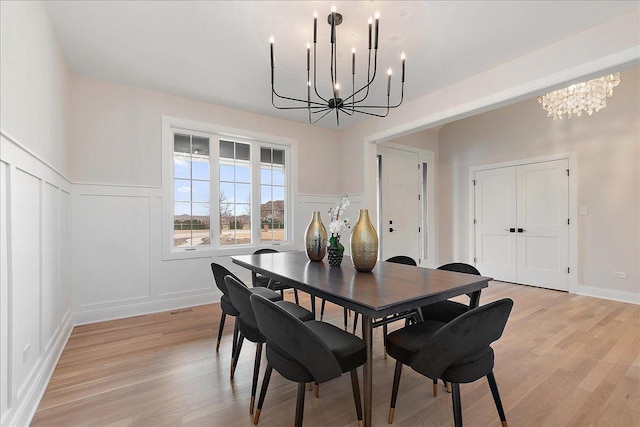 dining room with light hardwood / wood-style floors and a notable chandelier