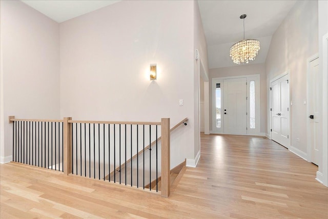 entryway with a towering ceiling, light hardwood / wood-style floors, and a chandelier