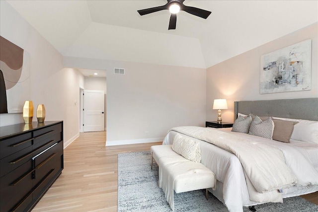 bedroom featuring ceiling fan, lofted ceiling, a raised ceiling, and light wood-type flooring