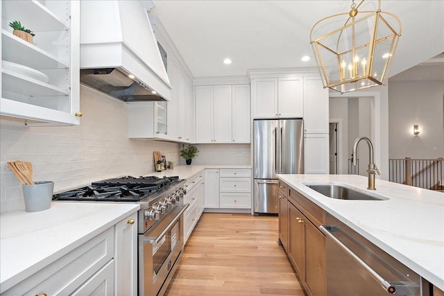 kitchen featuring high quality appliances, light stone countertops, sink, and white cabinets