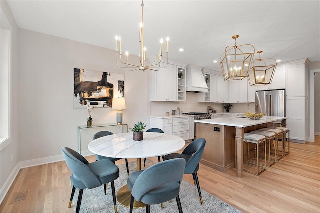 dining room featuring light wood-type flooring, sink, and an inviting chandelier