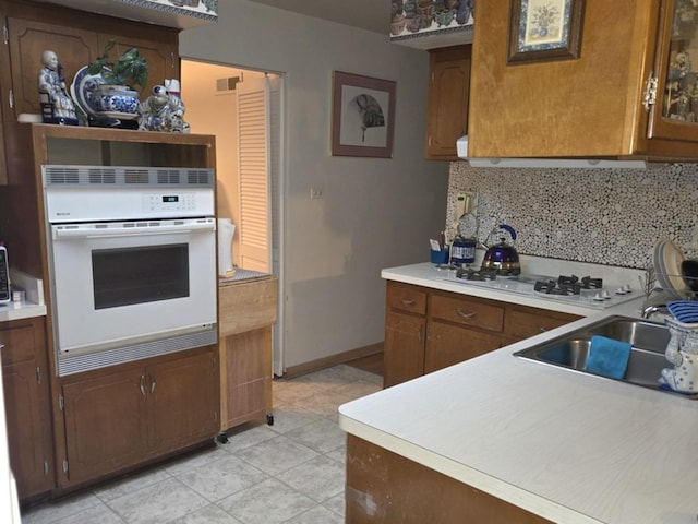 kitchen with backsplash, sink, and white appliances