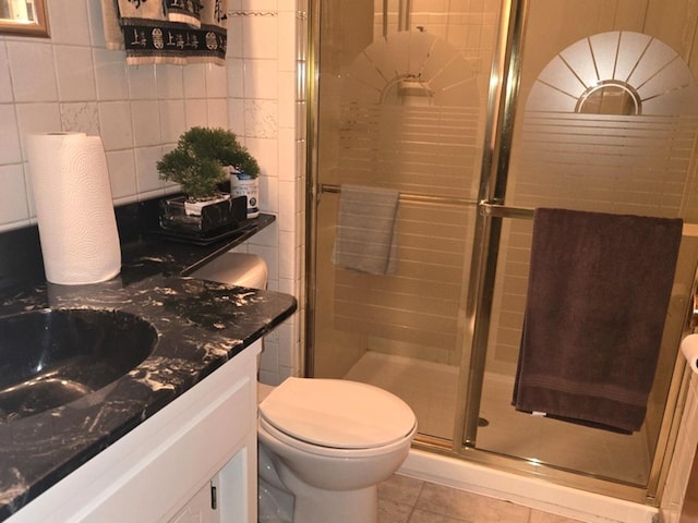 bathroom with tile patterned floors, an enclosed shower, vanity, tile walls, and toilet