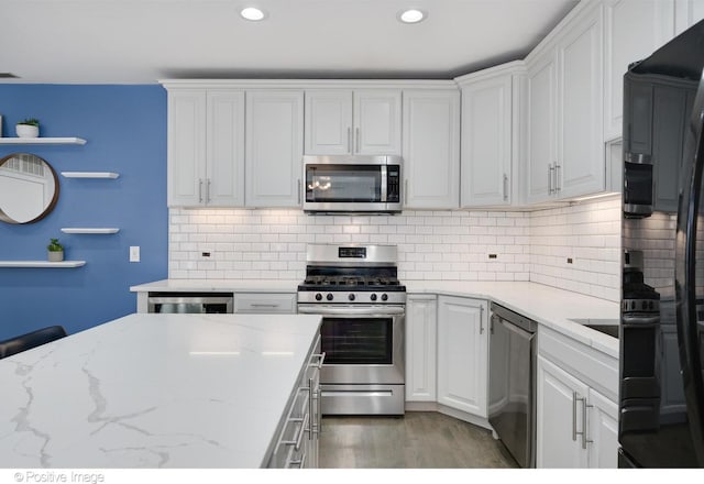 kitchen with white cabinets, stainless steel appliances, and light stone countertops