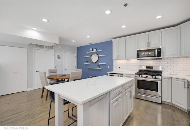 kitchen with decorative backsplash, appliances with stainless steel finishes, dark wood-type flooring, white cabinets, and a kitchen island