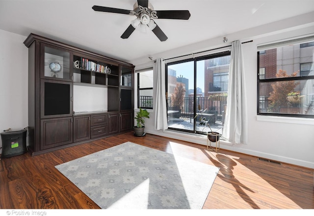 unfurnished living room with dark hardwood / wood-style flooring and ceiling fan