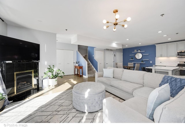 living room with light hardwood / wood-style floors, a notable chandelier, and a tiled fireplace