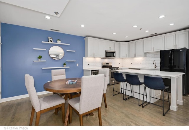 kitchen with appliances with stainless steel finishes, light hardwood / wood-style flooring, white cabinetry, and sink