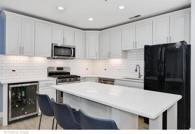 kitchen with white cabinets, appliances with stainless steel finishes, wine cooler, and sink