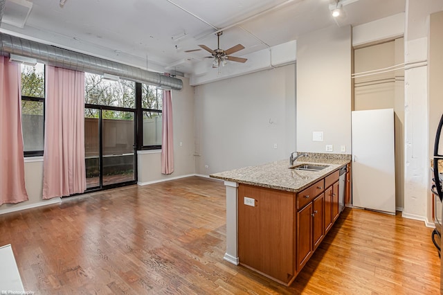 kitchen featuring ceiling fan, sink, light stone counters, stainless steel dishwasher, and light hardwood / wood-style floors