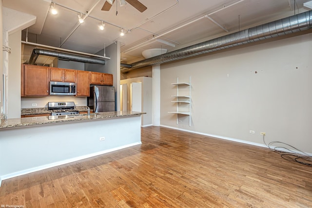 kitchen with ceiling fan, light stone countertops, stainless steel appliances, and light hardwood / wood-style flooring