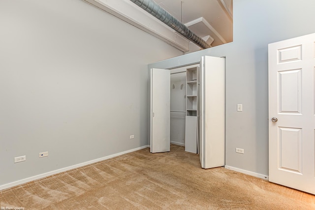 unfurnished bedroom with a high ceiling and light colored carpet