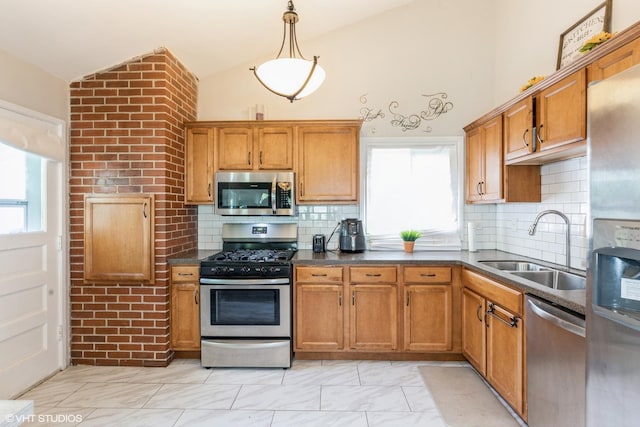 kitchen featuring plenty of natural light, lofted ceiling, sink, appliances with stainless steel finishes, and decorative light fixtures