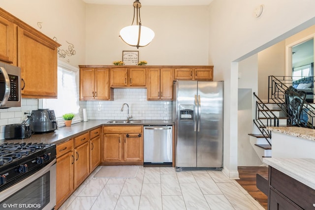 kitchen with tasteful backsplash, stainless steel appliances, sink, pendant lighting, and a high ceiling