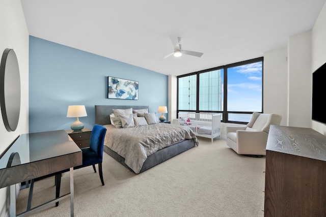 bedroom with ceiling fan, expansive windows, and light colored carpet