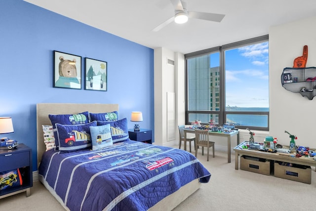 carpeted bedroom with expansive windows, ceiling fan, and a water view