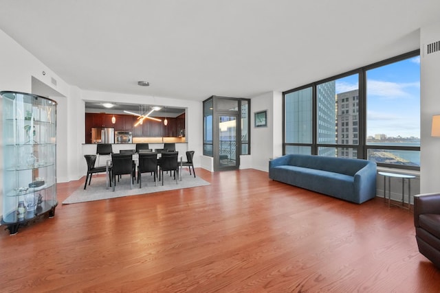 dining space with a wall of windows, a water view, and hardwood / wood-style flooring