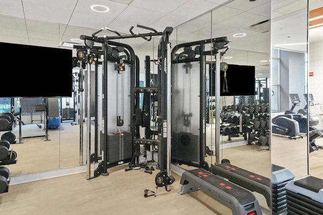 workout area with a paneled ceiling and light hardwood / wood-style floors