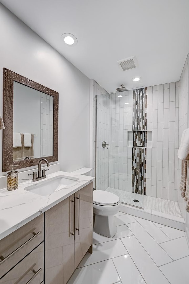 bathroom featuring a tile shower, vanity, toilet, and tile patterned floors