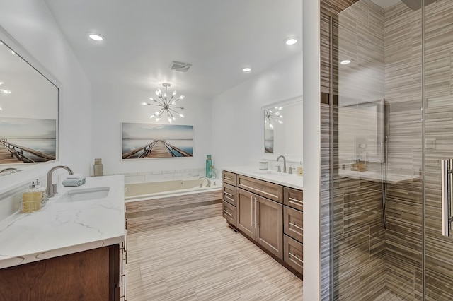 bathroom featuring a chandelier, vanity, and separate shower and tub