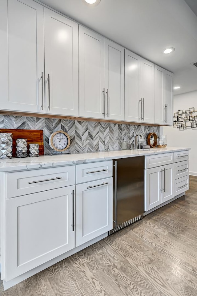 kitchen with high end refrigerator, backsplash, sink, light hardwood / wood-style flooring, and white cabinetry