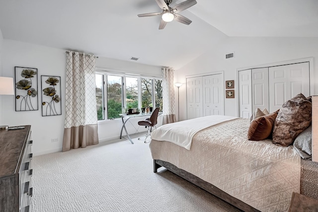 carpeted bedroom featuring two closets, vaulted ceiling, and ceiling fan